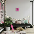 Pink wall clock on a shelf with decorative items